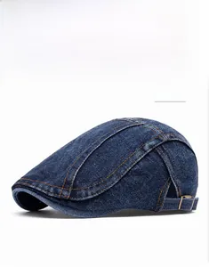 Detail view of deep blue denim flat cap featuring adjustable copper metal buckle