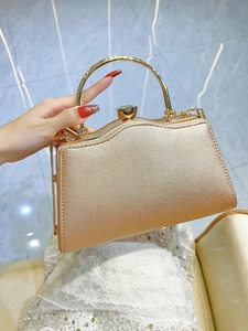 Detail of a gold metallic evening clutch bag with top handle and twist lock closure
