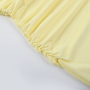 Makroaufnahme elastischer Raffungen an einem hellgelben figurbetonten Halter-Kleid