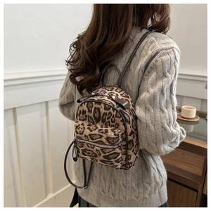 Close-up of leopard print mini backpack worn by model with grey winter sweater