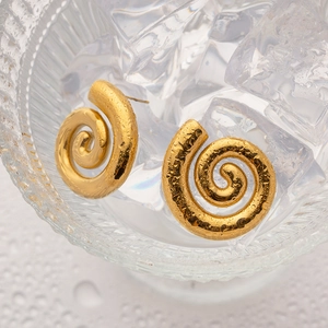 Macro shot of 18K gold spiral stainless steel earrings on ice cubes with water drops