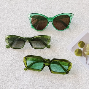 Three pairs of trendy green oval and cat-eye sunglasses in various shades on white background