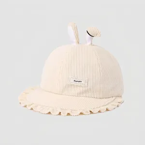 Détail d'un chapeau enfant en velours côtelé blanc cassé avec oreilles de lapin et volants
