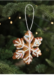 Detailed view of a glittery snowflake cookie ornament hanging on a green Christmas tree