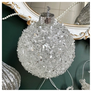 Close-up of sparkling silver Christmas ball with glitter texture on dark green background