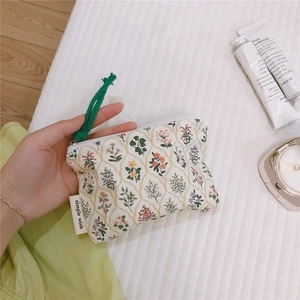 Detail of floral cotton mini pouch with green cord zipper pull and simple wish label