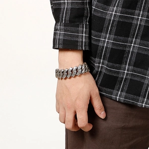 Detail of chunky stainless steel curb bracelet with intricate floral engraving