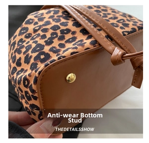 Detail view of leopard print bucket bag featuring brown leather base and gold metal studs
