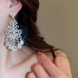 Close-up of elegant silver floral tassel earrings with rhinestones on a female model