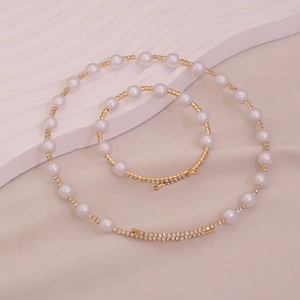Detailed view of the gold chain necklace and bracelet set with pearls and zircons