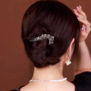 Elegant twist hair clip with grey rhinestones worn by a model in a sophisticated bun hairstyle