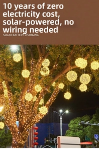 Catena luminosa solare a sfere di rattan con luce gialla calda su alberi da giardino