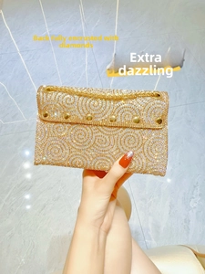 Detail of gold rhinestone clutch bag featuring spiral crystal patterns and metal chain strap