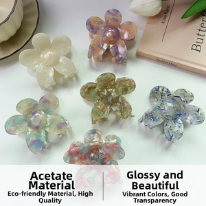 Close-up of floral acetate hair claws in various gradient colors on a beige book