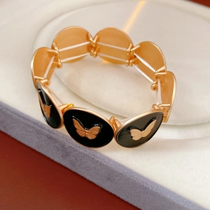 Macro detail of golden vintage bracelet featuring black oval inlay and butterfly relief