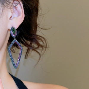 Vue détaillée de boucles d'oreilles géométriques évidées avec zircons colorés sur un modèle