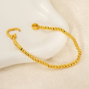 Detailed close-up of golden stainless steel ball chain bracelet with OT toggle clasp