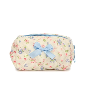Quilted floral cotton makeup pouch with blue bow detail and zipper on white background