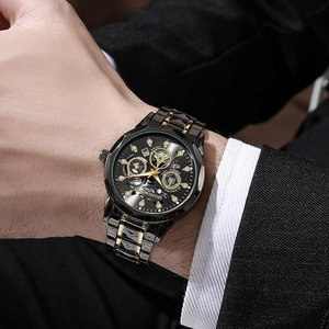 Detail van een luxe herenhorloge met zwart-gouden skelet wijzerplaat op de pols