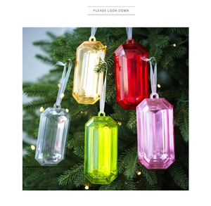 Primer plano de cinco adornos navideños de gemas de colores colgados en un árbol