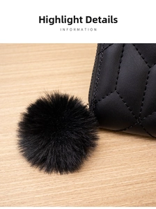 Detail of black quilted leather wallet with fluffy pompom and fine embroidery stitches