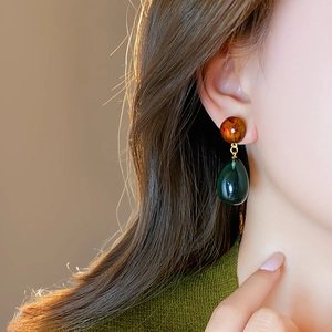 Close-up of vintage resin drop earrings with amber beads and dark green pendants