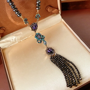 Gros plan d'un collier vintage avec perles noires et pierres violettes dans son écrin