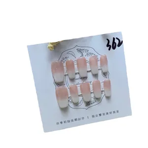 Pink and white ombre press-on nails with glossy long oval shape on a display card