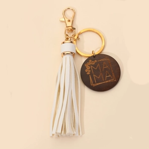 Detail of white PU leather tassel and wooden MAMA keychain with floral engraving