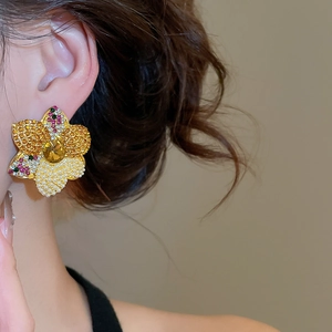 Close-up of elegant floral earring with colorful crystals and pearl on ear