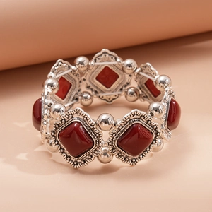 Macro detail of vintage silver-tone geometric bracelet with red resin stones and carvings