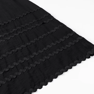 Primo piano del tessuto nero con ricami ondulati paralleli e dettagli sartoriali rifiniti