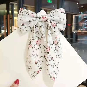 Detail of floral chiffon bow hair clip with rose pattern and long flowing ribbons