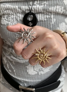 Close-up of gold and silver sun rings featuring spiral texture and radiating rays