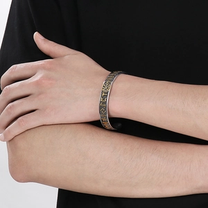 Detail of Viking compass and Odin runes on a silver and gold textured cuff bracelet
