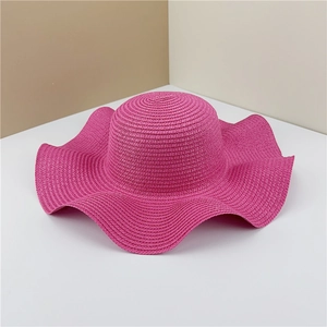 Detail of rose pink straw hat with wide wavy brim and high-quality handwoven texture