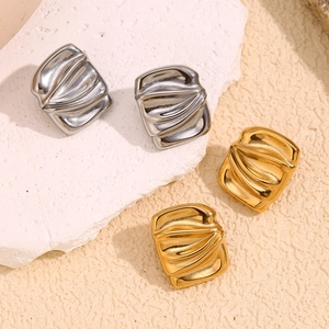 Macro view of geometric gold and silver stud earrings with wavy metallic texture