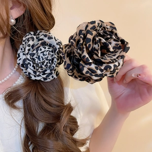 Gros plan d'une pince à cheveux motif léopard avec pétales de fleurs en tissu 3D