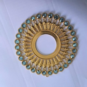 Macro shot of circular golden metal accessory featuring blue rhinestones and sunburst pattern