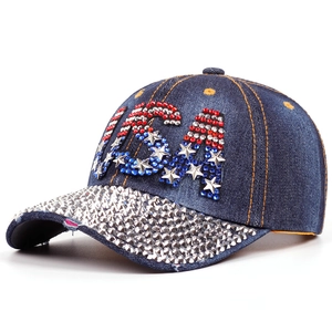 Detailed shot of USA rhinestone lettering and studded brim on navy denim baseball cap