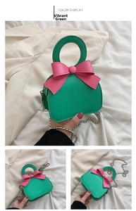 Detail view of mini vitality green handbag with pink bow and silver bead chain strap