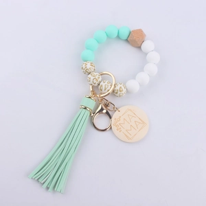 Detail of beaded keychain with mint silicone beads, MAMA wood charm, and soft tassel