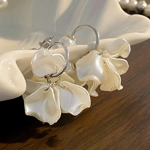 Orecchini pendenti a fiore bianchi con petali perlati e cerchi in argento in un piatto