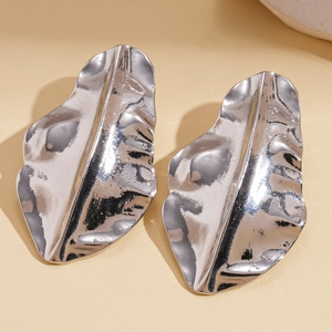 Detail shot of silver leaf-shaped earrings with unique crinkle texture and metallic finish