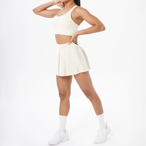 Détail d'un ensemble de sport blanc crème avec haut croisé et jupe plissée