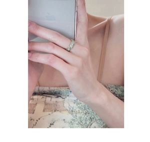 Close-up of a gold crosshatch ring with light green enamel inlay on model's finger