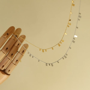 Detailed close-up of gold and silver plated tassel necklaces on a wooden model