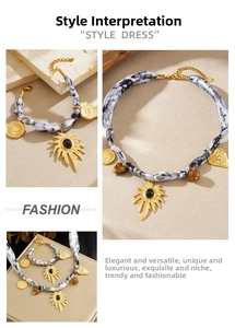 Detail of bohemian gold sunburst necklace with black gem and ink-print silk ribbon