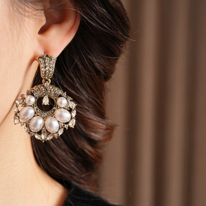 Gros plan de boucles d'oreilles vintage dorées avec perles et strass sur un mannequin