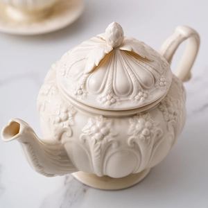 Detailed view of an ivory ceramic teapot with embossed patterns and flower bud lid